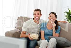 Lovely couple laughing while relaxing in front of the television
