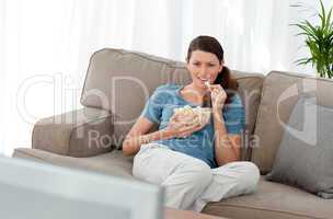 Attractive woman watching television and eating pop corn on the
