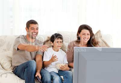 Family laughing while watching television together