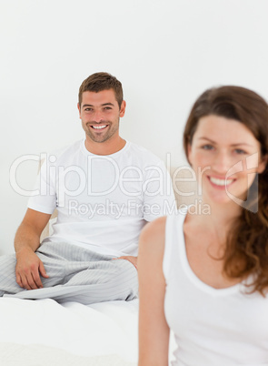 Cheerful couple relaxing together in their bedroom in the mornin