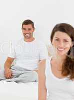 Cheerful couple relaxing together in their bedroom in the mornin