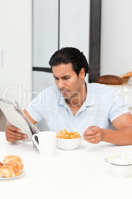 Serious man reading the newspaper while eating cereals