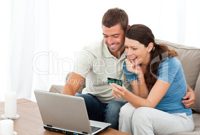 Happy couple looking at their accounts online sitting on the sof