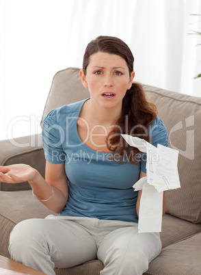 Worried woman misunderstanding her bills sitting in the living r