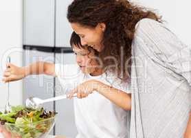 Happy mother and son preparing a salad together