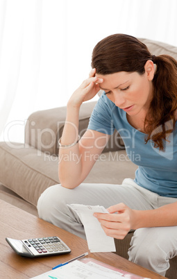 Concentrated woman looking at her bills sitting in the living-ro