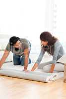 Lovely couple rolling a carpet together in the living room