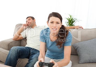 Serious woman playing video game while her boyfriend waiting for