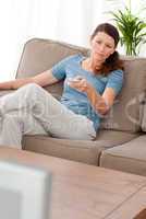 Serious woman changing channel while relaxing in the living-room
