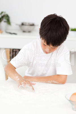 Cute boy playing with floor while cooking alone