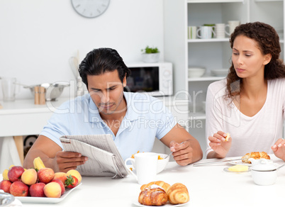 Concentrated couple reading the newspaper together during breakf