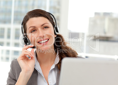 Thoughtful businesswoman talking on the phone while working on h