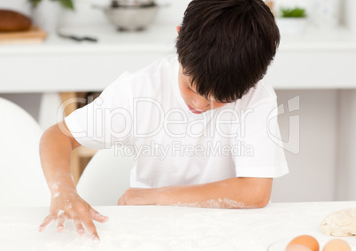 Adorable boy preparing a dough alone