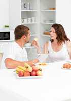 Cute woman giving bread to his husband during breakfast in the k