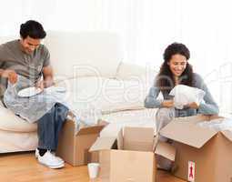 Joyful couple packing glasses together in the living room