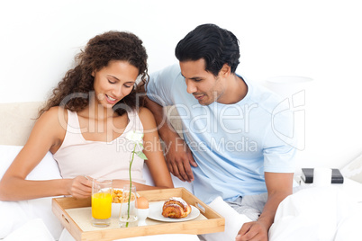 Cute woman eating cereals for breakfast lying on her bed