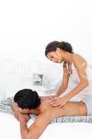 Attentive woman doing a massage to her boyfriend on their bed