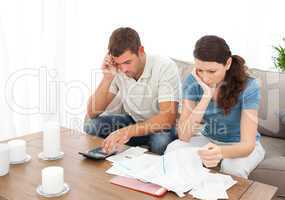 Desperate couple doing their accounts sitting on the sofa
