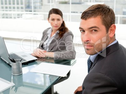 Serious businesspeople sitting around a table and looking at the