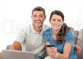 Cute couple with their laptop and credit card sitting in the liv