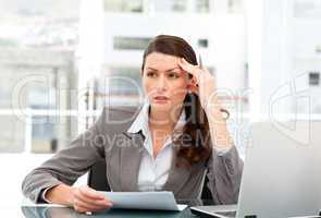 Serious female executive finding ideas while working at her desk