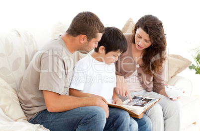 Happy family looking at a photo album together on the sofa