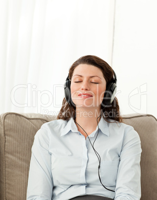 Relaxed woman listening music with headphones in the living room