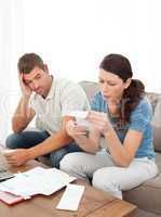 Stressed couple doing their accounts sitting on the sofa