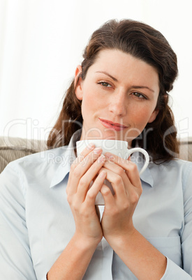 Pretty woman holding a cup of coffee sitting on the sofa