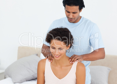 Handsome man doing a massage to his beautiful wife on their bed