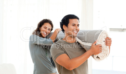 Happy couple holding a carpet together in their new living-room