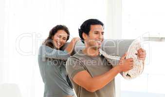 Happy couple holding a carpet together in their new living-room