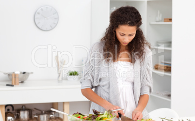 Concentrated woman cutting vegetables in the kitchen