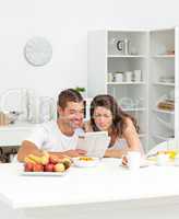 Happy couple reading the newspaper in the kitchen