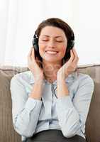 Smiling woman listening music with heaphones in the living room
