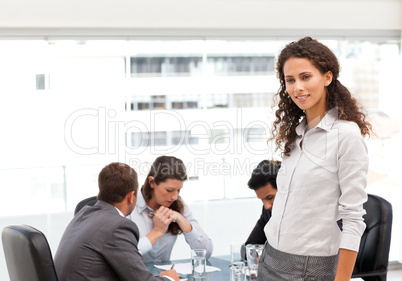 Attractive manager standing in the office while her team working