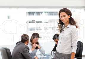 Attractive manager standing in the office while her team working