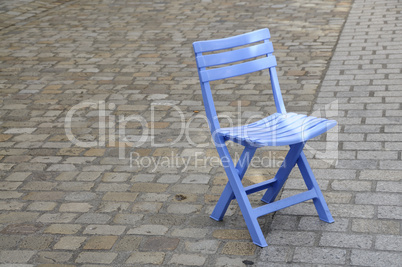 Blue chair on cobbled pavement