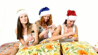Young girls in santa hat eat chocolate on pillows - christmas theme