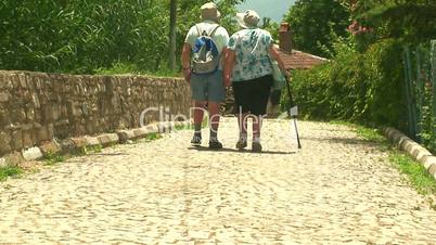 Elderly married couple walking on cobbled road 3