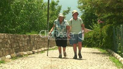 Elderly married couple walking on cobbled road 4