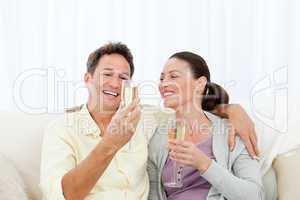 Happy couple tasting champagne sitting on the sofa