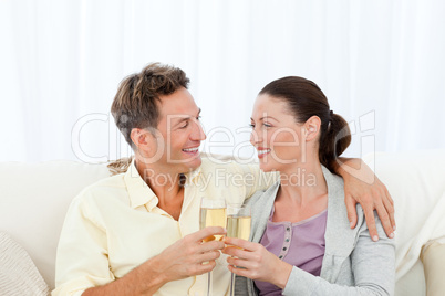 Cute couple drinking champagne while relaxing on the sofa