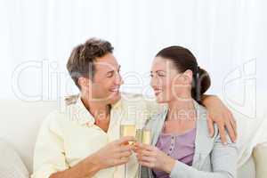 Cute couple drinking champagne while relaxing on the sofa
