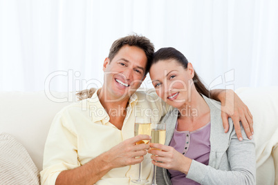 Portrait of a couple holding flutes of champagne on the sofa