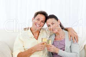 Portrait of a couple holding flutes of champagne on the sofa