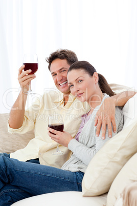 Happy couple enjoying their glasses of red wine on the sofa