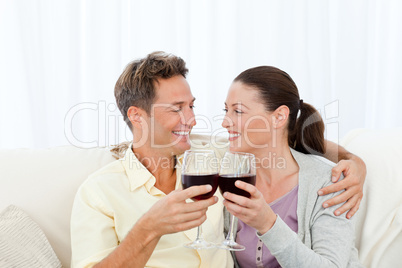 Passionate couple drinking red wine while relaxing on the sofa