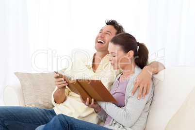 Man laughing while looking at a photo album with his girlfriend