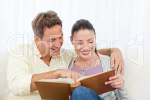 Couple smiling while looking at pictures on a photo album